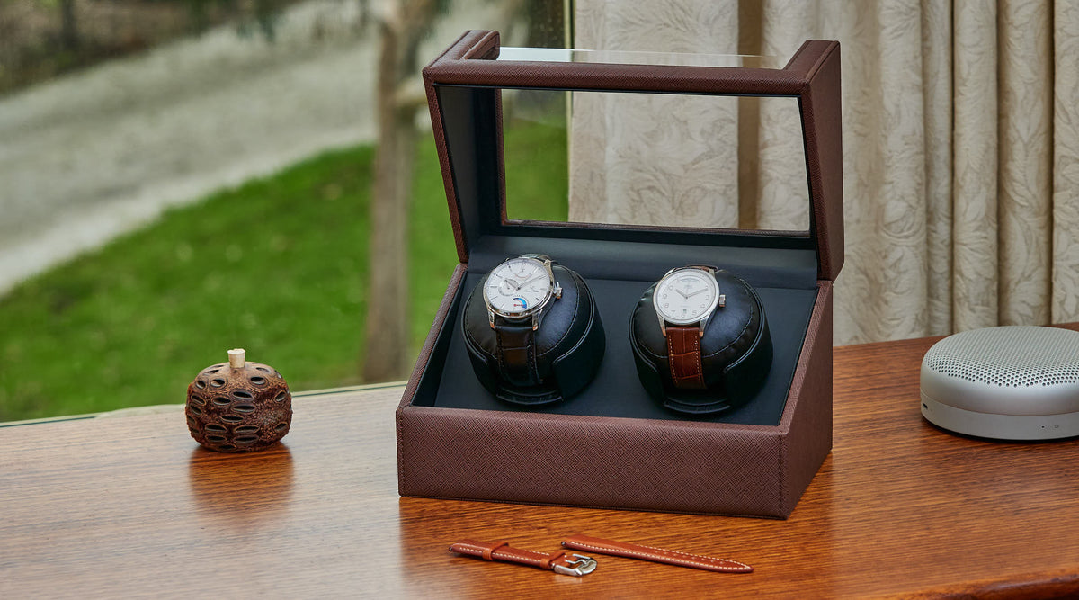 Two automatic watches turning in a leather watch winder on a sideboard